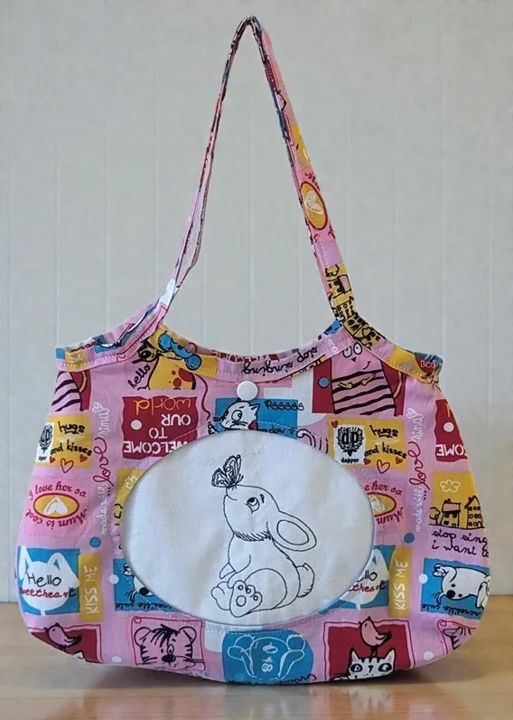 Kindertasche aus bunter Baumwolle mit Comic-Motiven und gesticktem Hasenbild vorne.